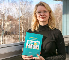 Leealaura Leskelä pitelee käsissään Selkokieli - Saavutettavan kielen opas -teosta.