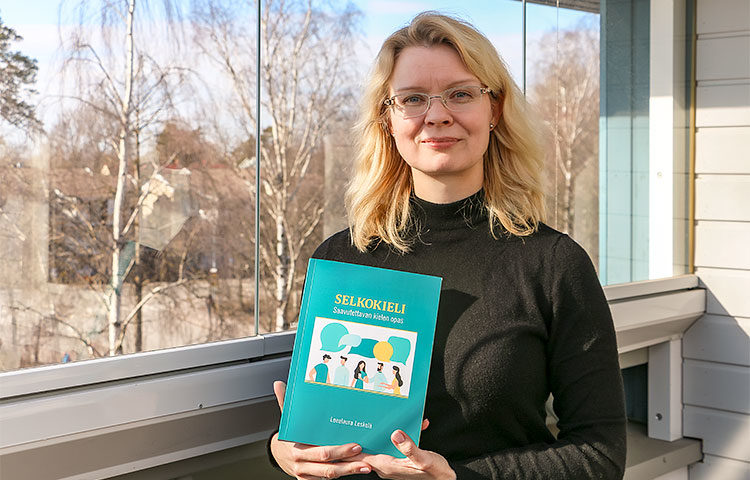 Leealaura Leskelä pitelee käsissään Selkokieli - Saavutettavan kielen opas -teosta.