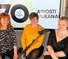 Kolme naista istuu mikrofonin takana.