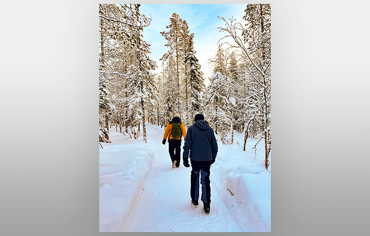 Kaksi ihmistä kävelee talvella metsässä.