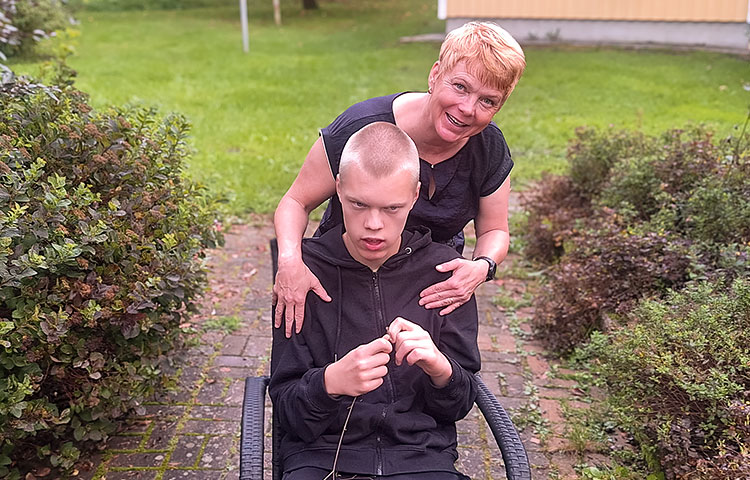 Nuori mies istuu tuolilla, takana nainen.
