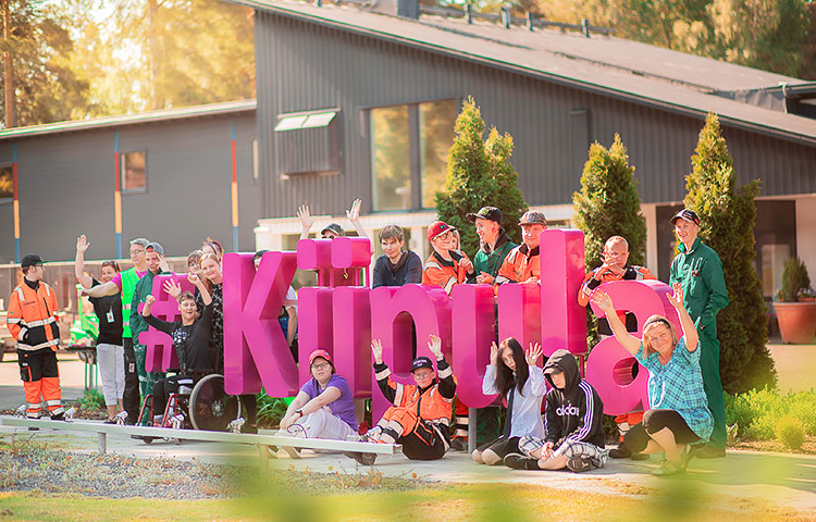 Ryhmä ihmisiä kokoontuneena suuren Kiipula-kyltin ympärille.