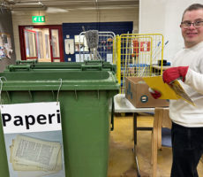 Mies kirjan kanssa paperiroskiksen vieressä.