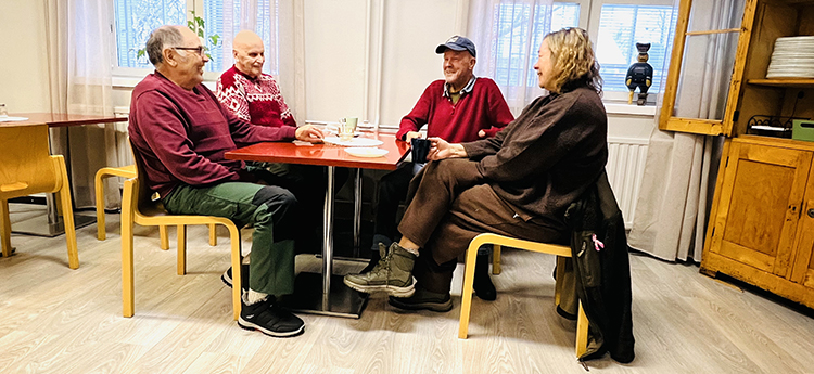 Neljä ihmistä istuu keskustelemassa pöydän ääressä.