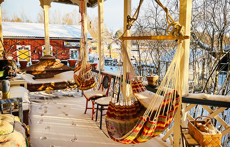 Talvinen ulkokuisti, jossa lumen peittämiä kalusteita ja kaksi riippumattoa.