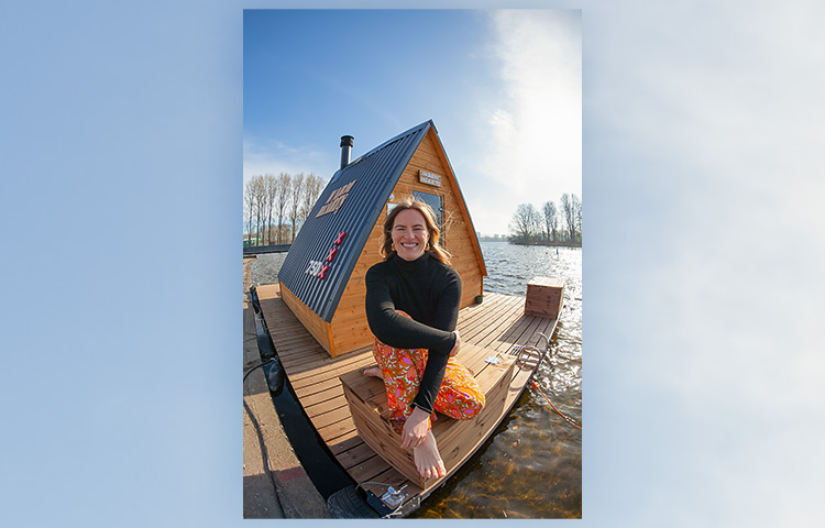 Elsa Havas istuu saunalautan edessä ja hymyilee.