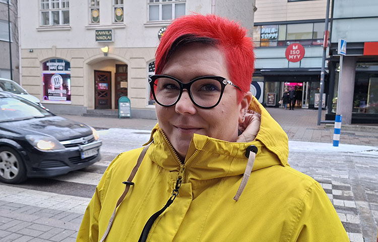 Punatukkainen nainen keltaisessa takissa ulkona kadulla.