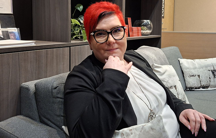 Punatukkainen nainen istuu sohvalla.