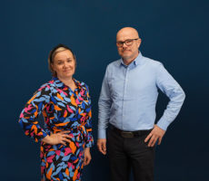 Kaksi henkilöä seisoo ja katsoo kameraan.