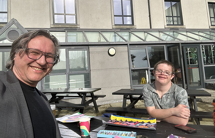 Kaksi henkilöä istuu pöydän ääressä iloisina.