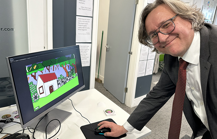 Mies tietokoneen ääressä , ruudulla näkyy piirroskuva talosta.