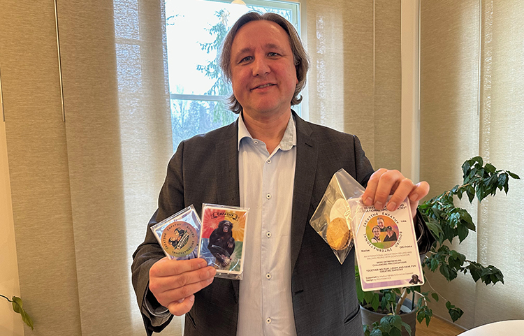 Mies esittelee kortteja ja tarroja ja jotain muuta muovipusseihin pakattuja pelin osia.