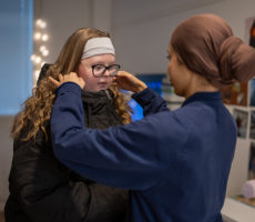 Kaksi henkilöä, toinen auttaa toista pukemisessa.