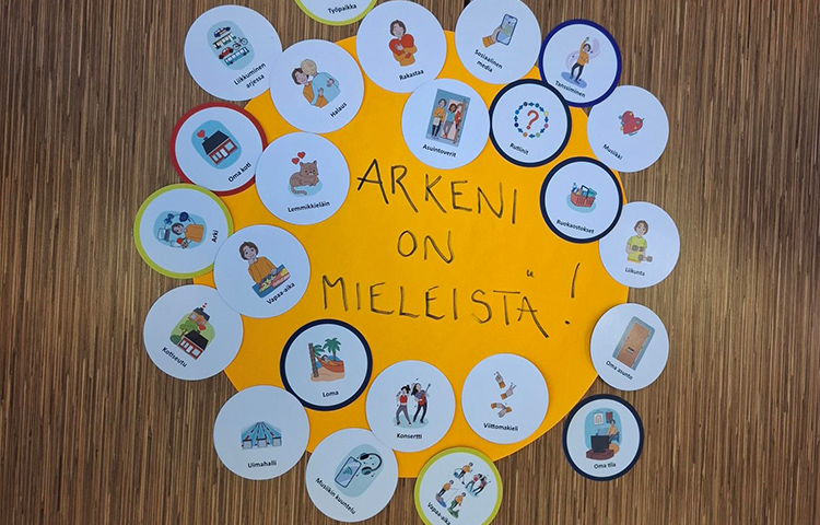 Pyöreitä kuvakortteja isomman paperin päällä. Siinä lukee Arkeni on mieleistä.